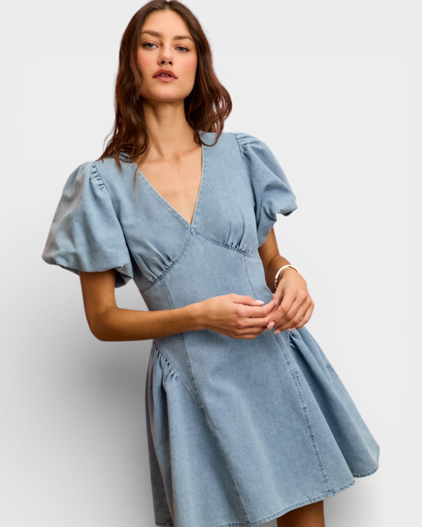 Woman wearing a light blue denim dress against a white background