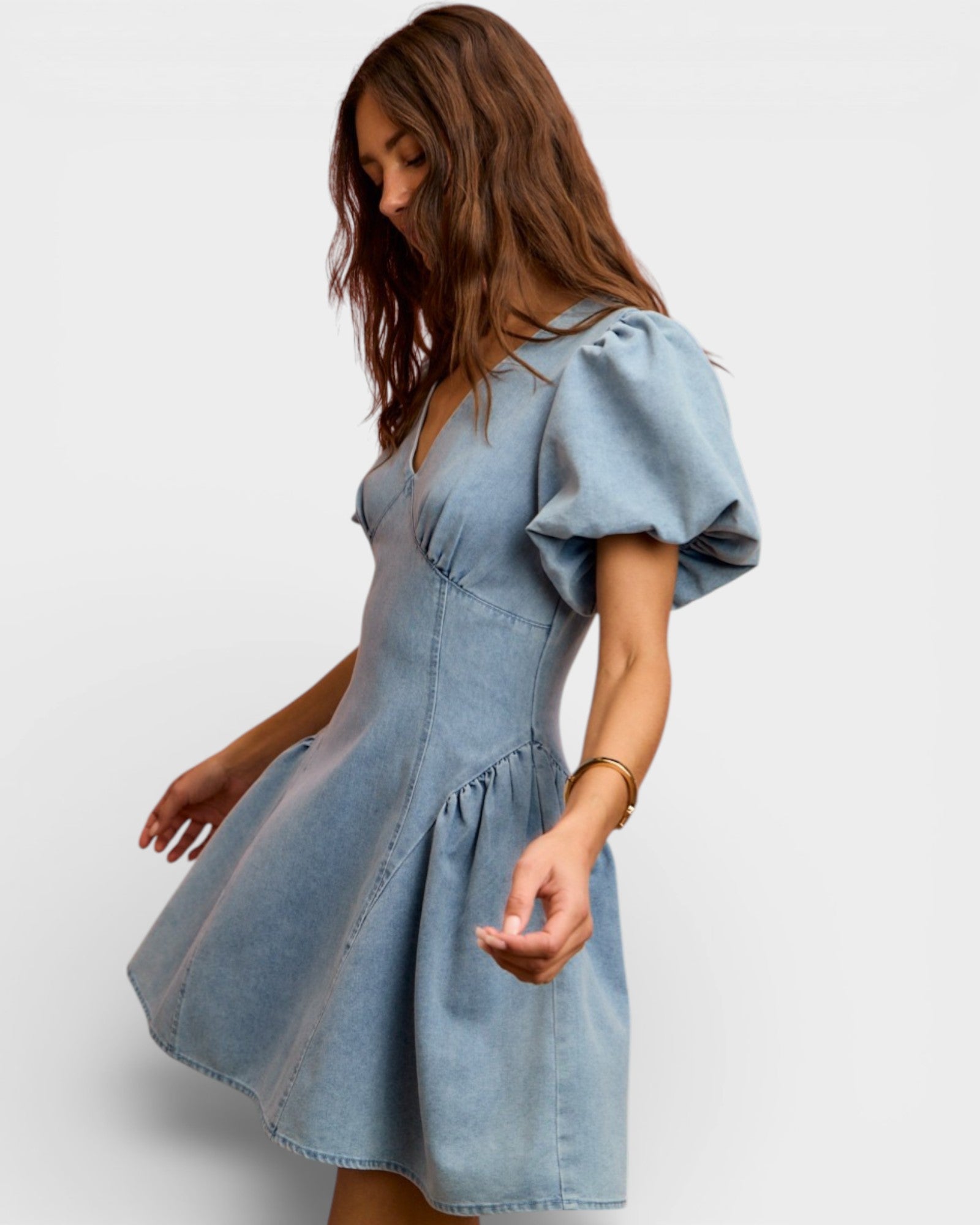 Woman wearing a light blue denim dress on a white background