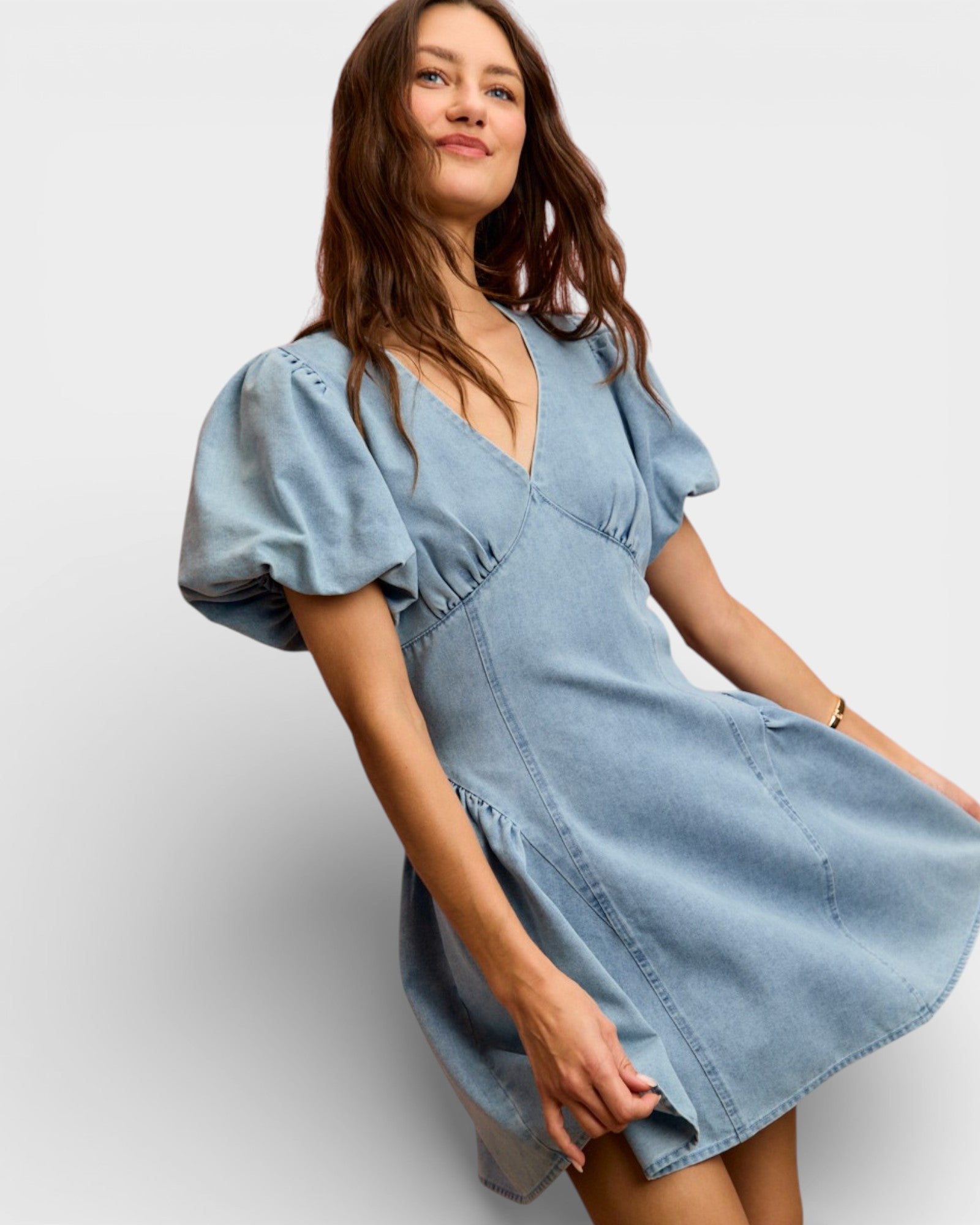 Woman wearing a light blue denim dress on a white background