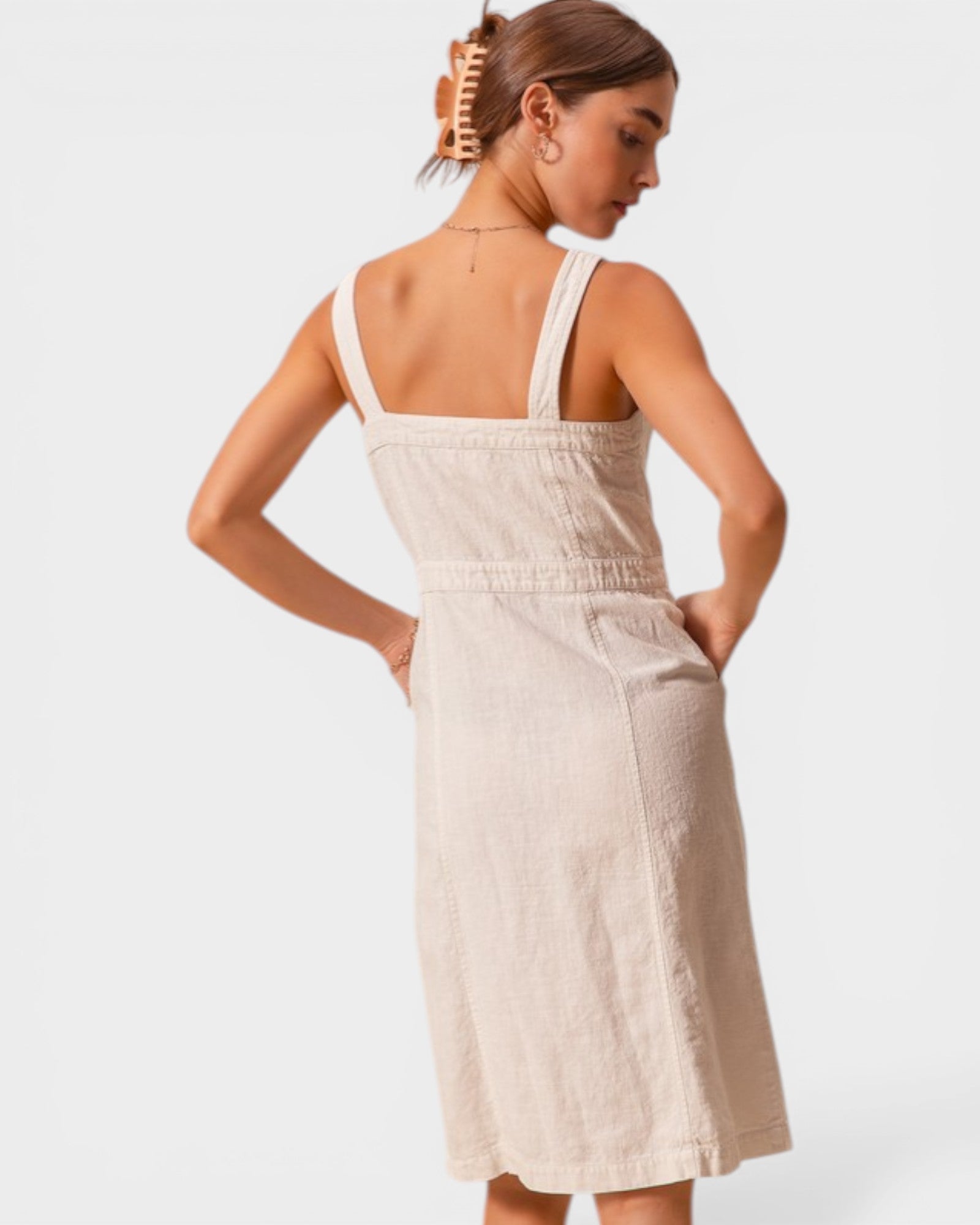 Woman wearing a beige dress with thin straps on a white background