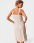 Woman wearing a beige dress with thin straps on a white background