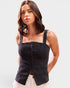 Woman wearing a black sleeveless top with button details on a white background