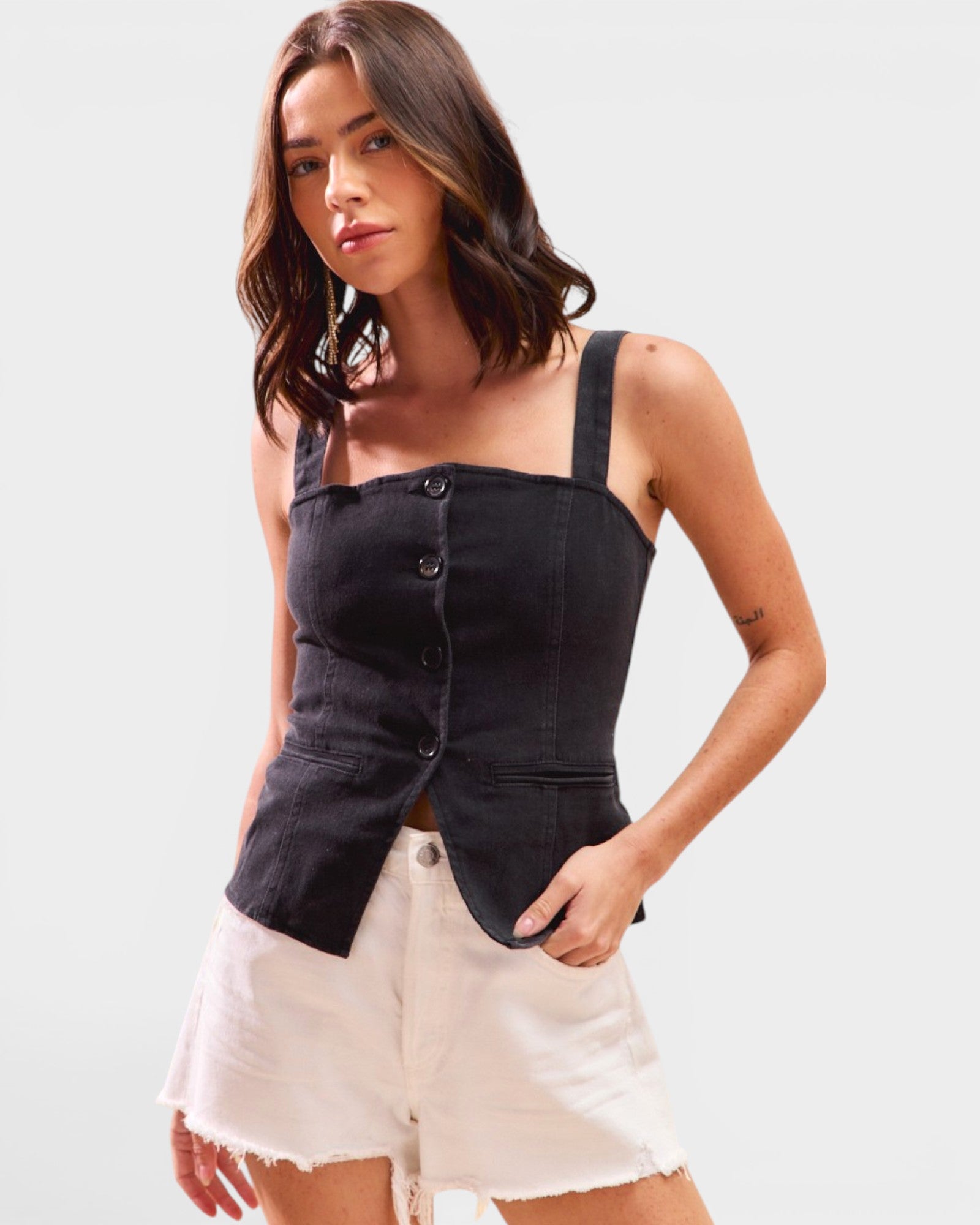 Woman wearing a black sleeveless top and white shorts on a light gray background