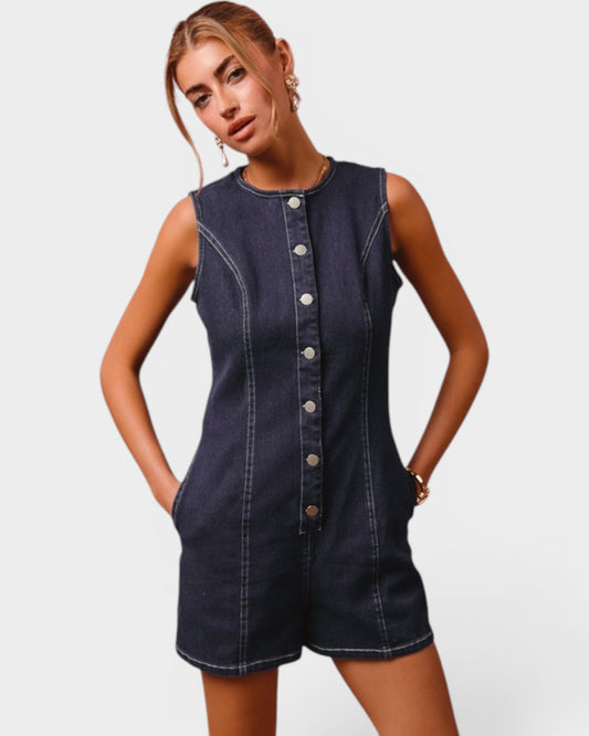 Woman wearing a denim romper with button details on a plain background