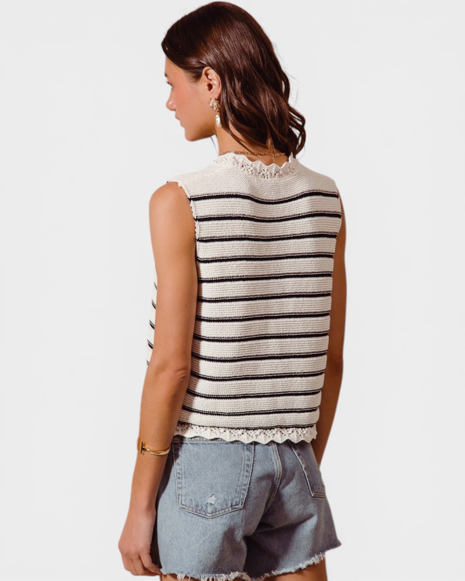 Woman wearing a striped sleeveless top and denim shorts on a white background