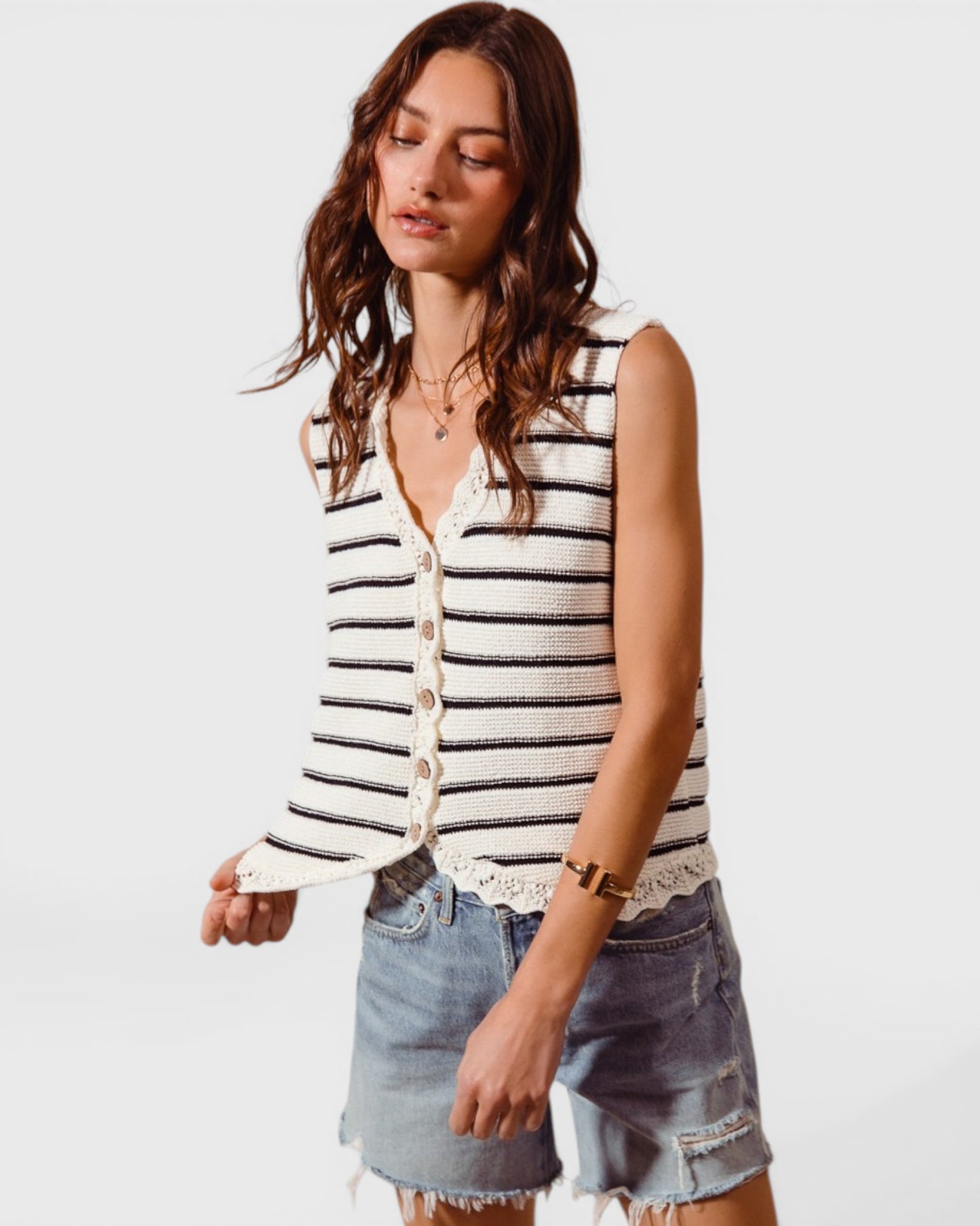 Woman wearing a striped sleeveless top and denim shorts on a white background