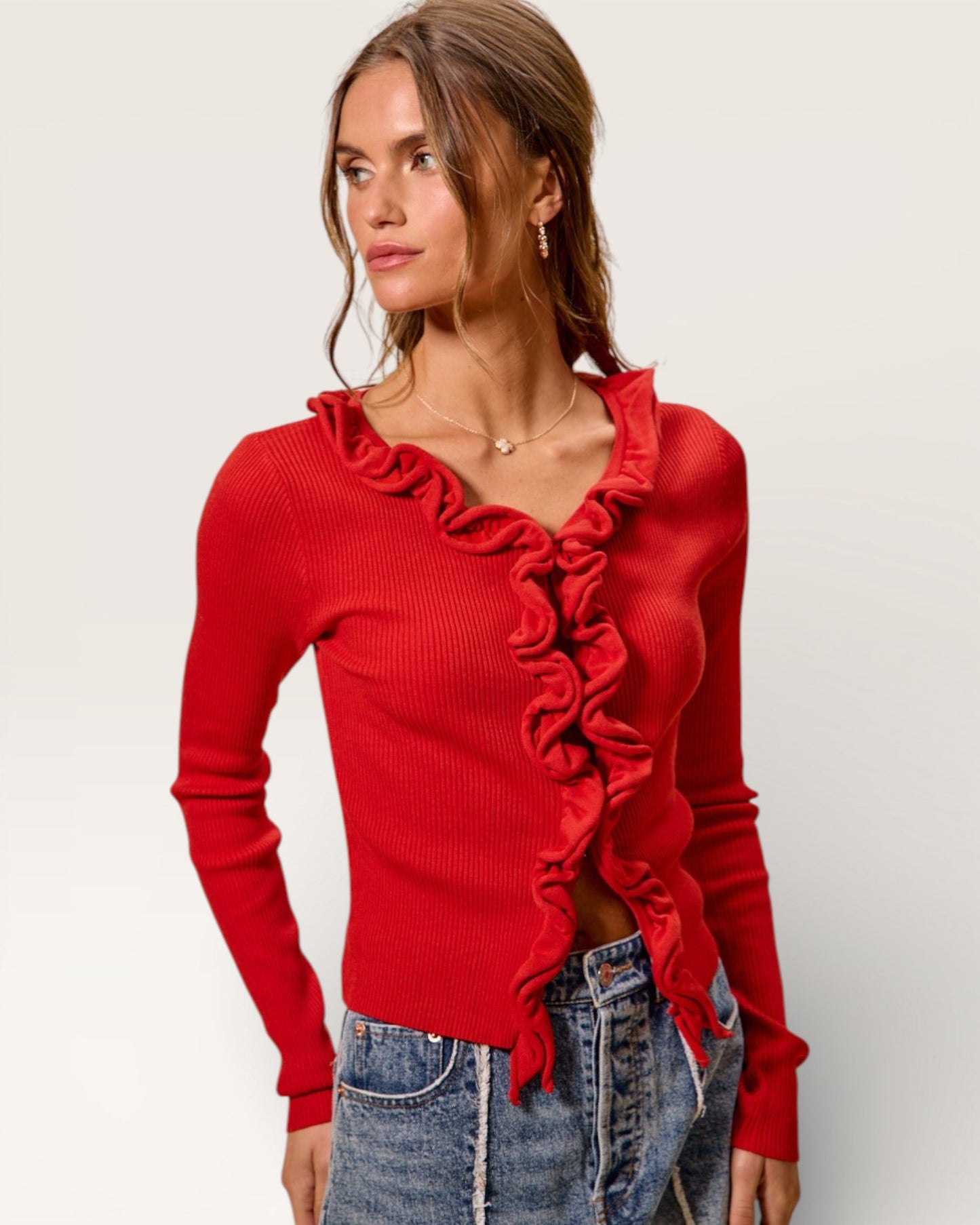 Woman wearing a red ruffled sweater against a plain background