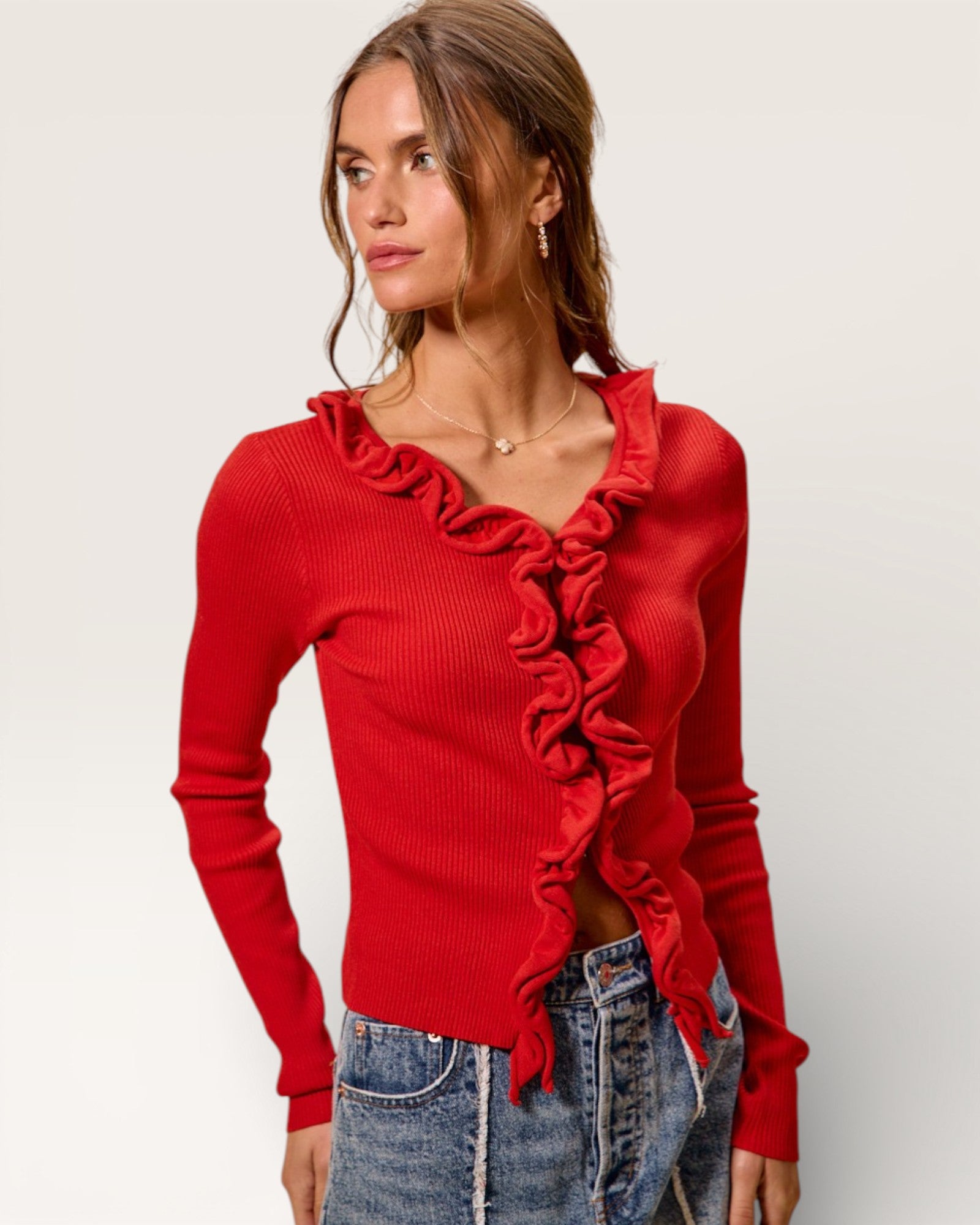 Woman wearing a red ruffled sweater against a plain background