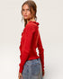 Woman wearing a red sweater with ruffled shoulders against a white background