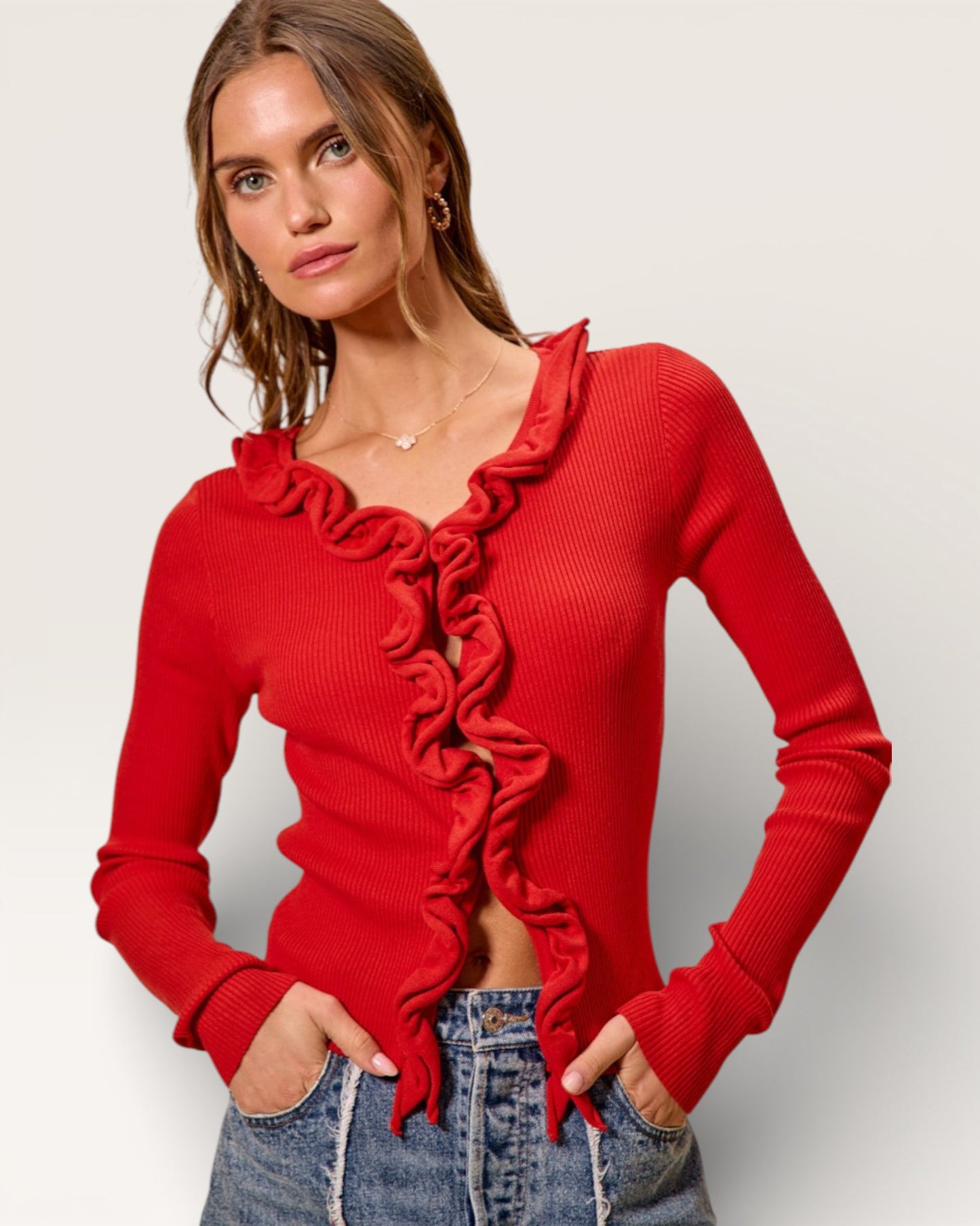 Woman wearing a red ruffled sweater against a plain background