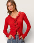 Woman wearing a red ruffled sweater against a plain background
