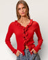 Woman wearing a red ruffled sweater against a plain background