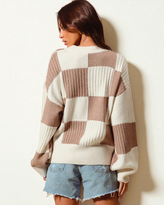 Woman wearing a checkered sweater and denim shorts against a plain background