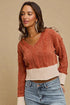Woman wearing a two-tone sweater with a beige and rust pattern against a beige background