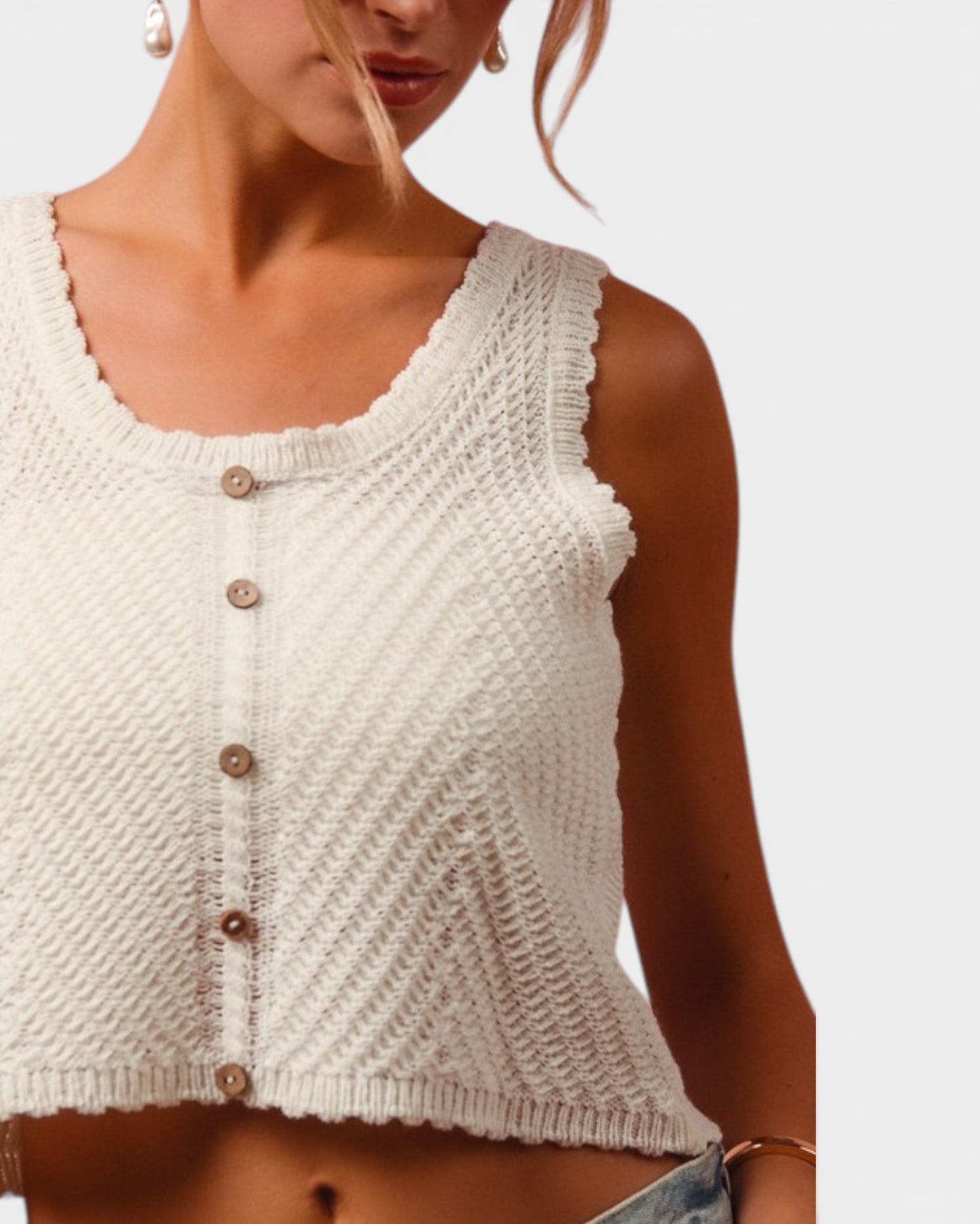 White knitted tank top worn by a person on a plain background