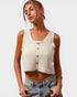 Woman wearing a cream knitted tank top and blue jeans on a plain background