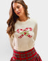 Woman wearing a cream sweater with candy cane design and plaid skirt on a white background