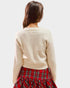 Person wearing a beige sweater and red plaid skirt on a white background