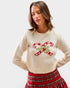 Woman wearing a cream sweater with candy cane design and plaid skirt on a white background