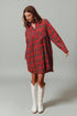 Woman wearing a red plaid dress and white cowboy boots on a gray background