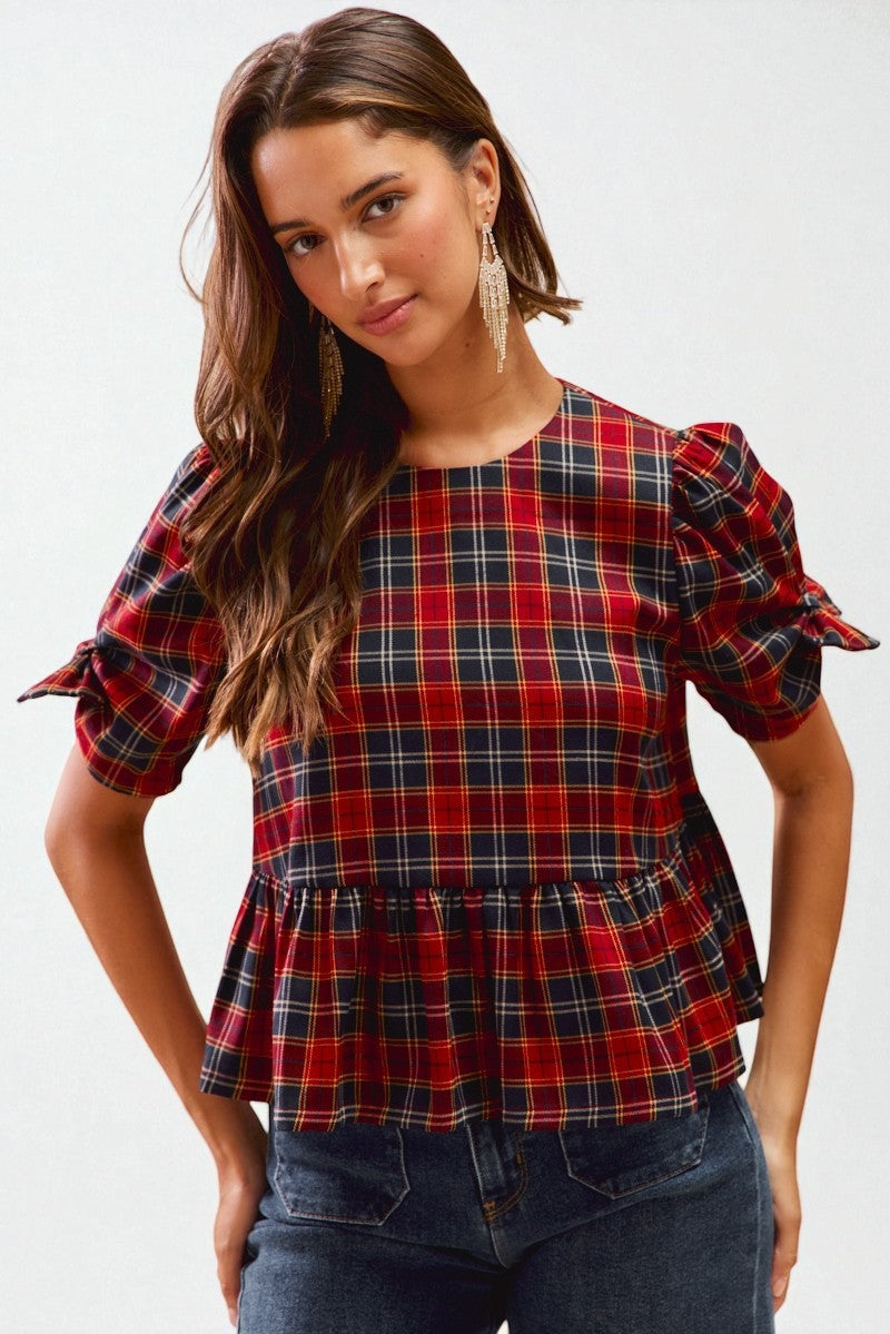 Woman wearing a red and blue plaid top with puffed sleeves on a white background