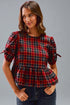 Woman wearing a red and blue plaid top against a gray background