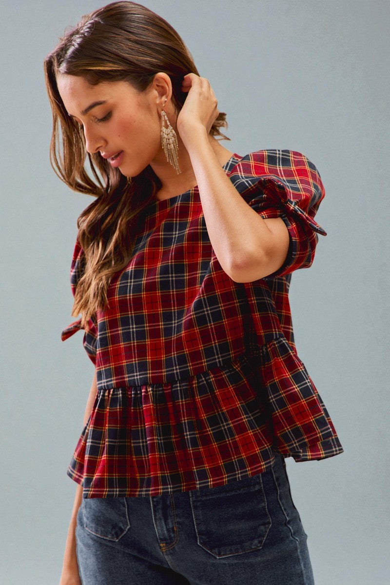 Woman wearing a red and blue plaid top against a gray background