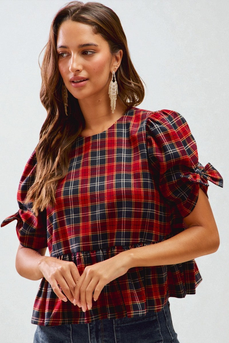 Woman wearing a red and blue plaid top with puffed sleeves on a white background