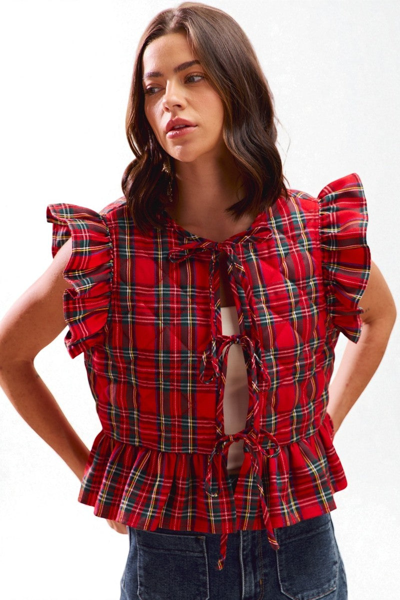 Woman wearing a red plaid top with ruffled sleeves on a white background