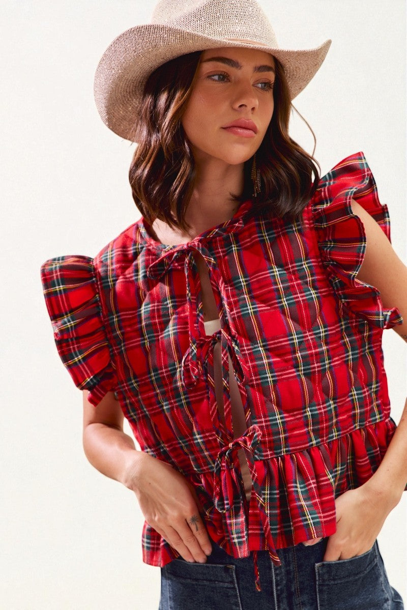 Woman wearing a red plaid blouse and cowboy hat against a white background