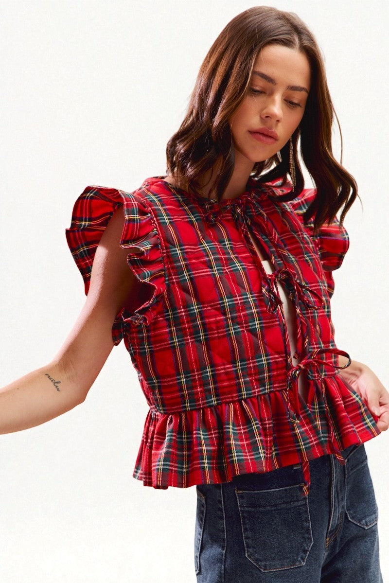 Woman wearing a red plaid blouse with puffed sleeves on a white background