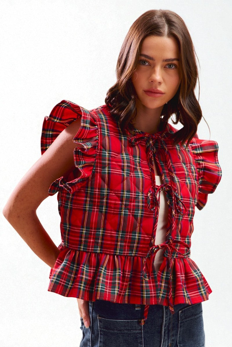 Woman wearing a red plaid blouse with ruffled sleeves on a white background