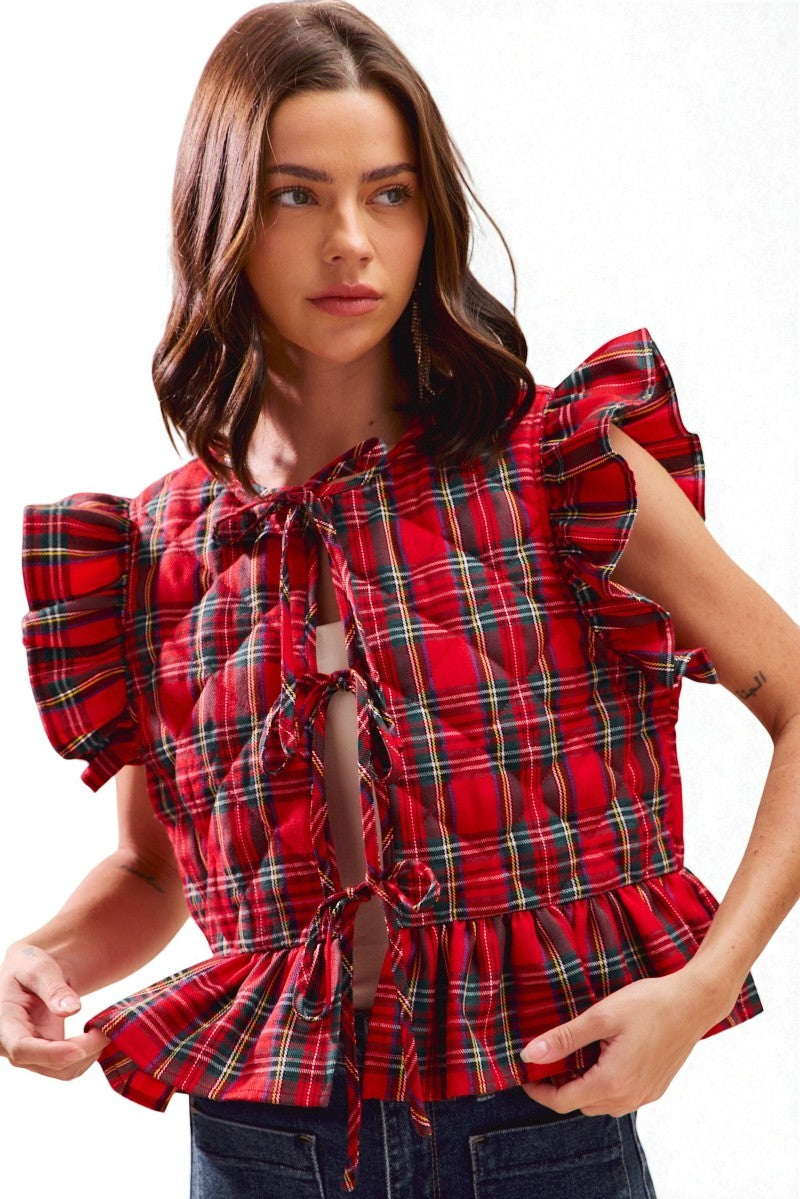Woman wearing a red plaid blouse with ruffled sleeves on a white background