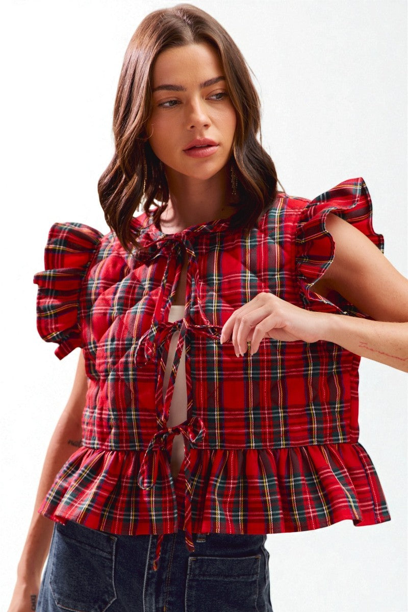 Woman wearing a red plaid blouse with ruffled sleeves on a white background