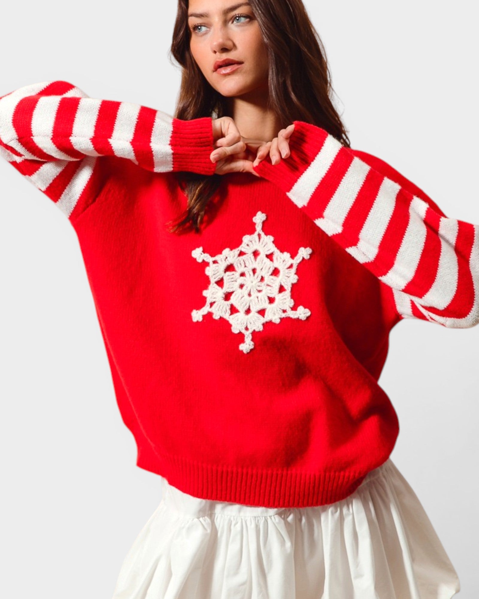 Person wearing a red sweater with white snowflake design on a plain background