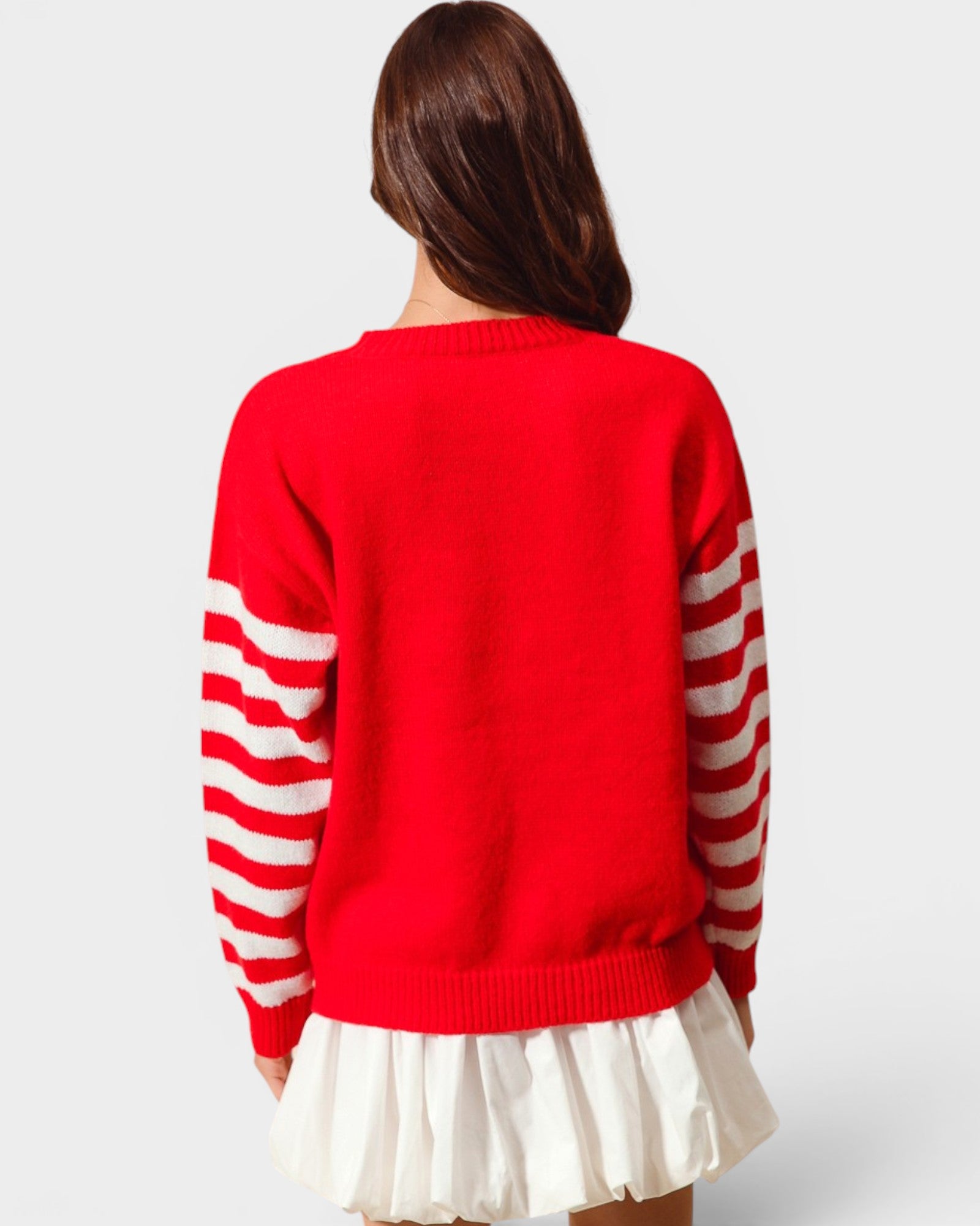 Person wearing a red sweater with white stripes on sleeves and a white skirt against a light gray background