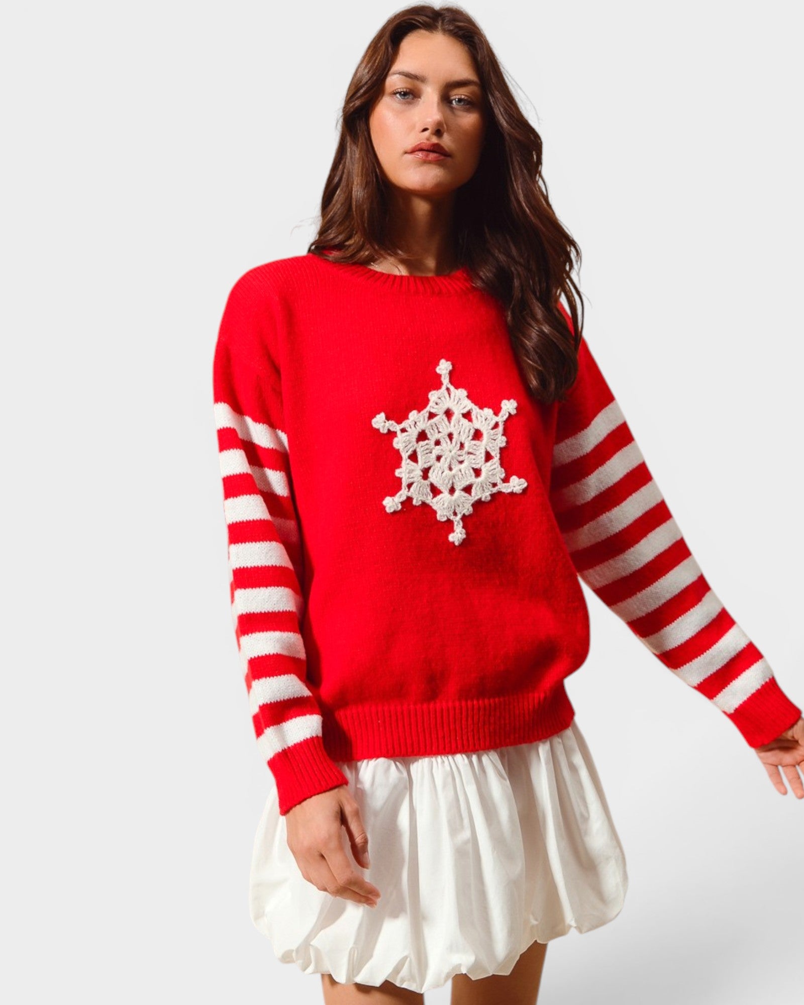 Woman wearing a red sweater with a white snowflake design on a plain background