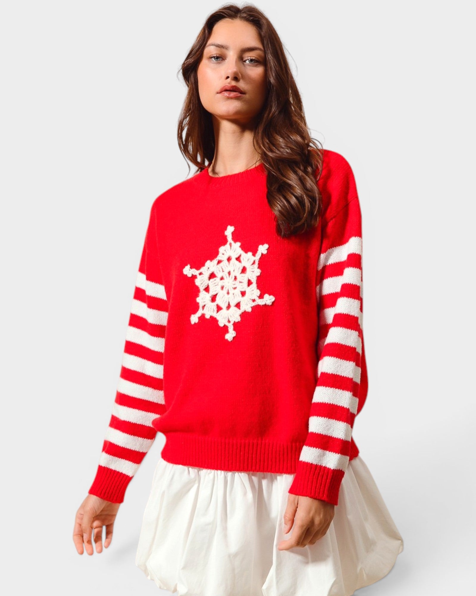 Woman wearing a red sweater with white snowflake design and stripes on a white background