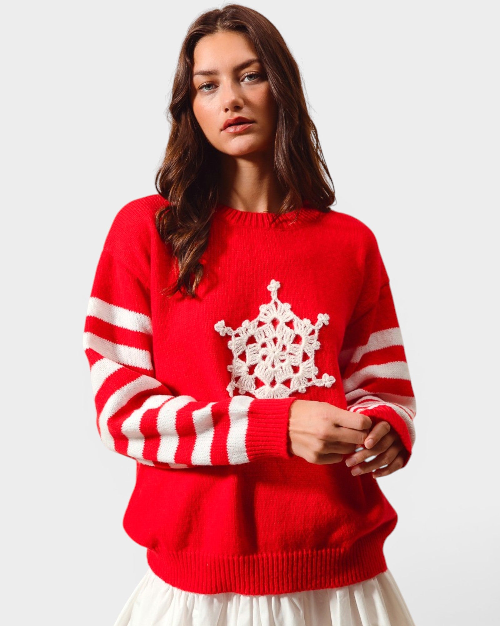 Woman wearing a red sweater with white snowflake design on a plain background