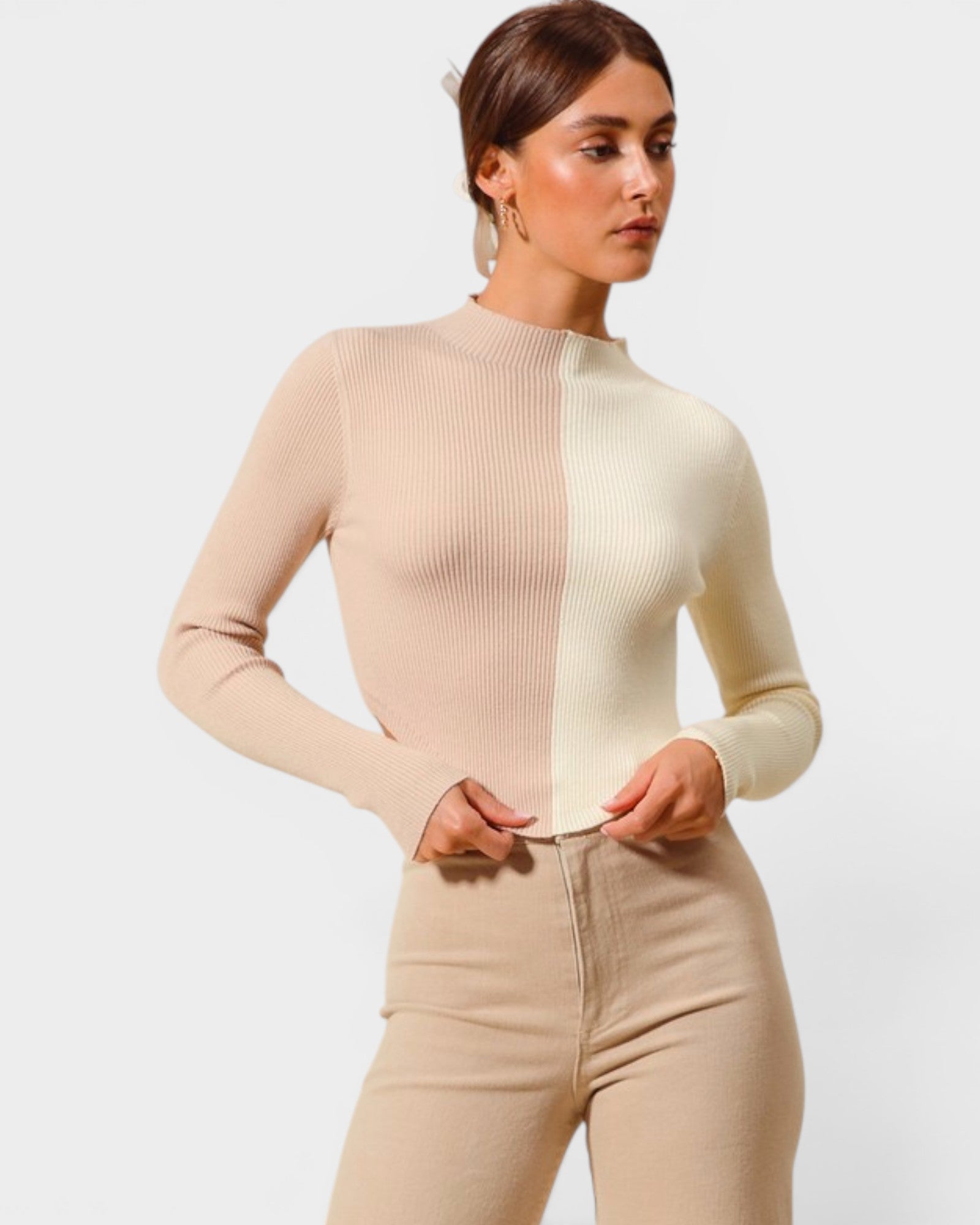 Woman wearing a beige ribbed sweater and pants on a light background