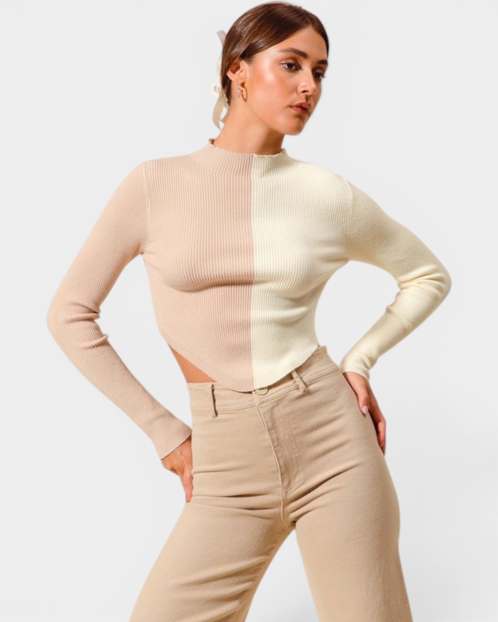 Woman wearing a two-tone beige sweater and pants against a plain background