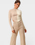 Woman wearing a beige long-sleeve top and pants on a white background