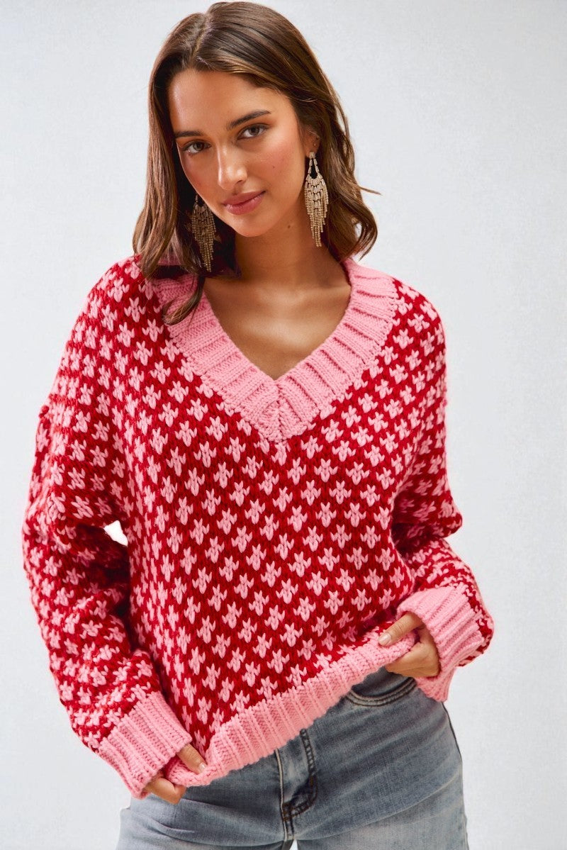 Woman wearing a red and pink patterned sweater against a plain background
