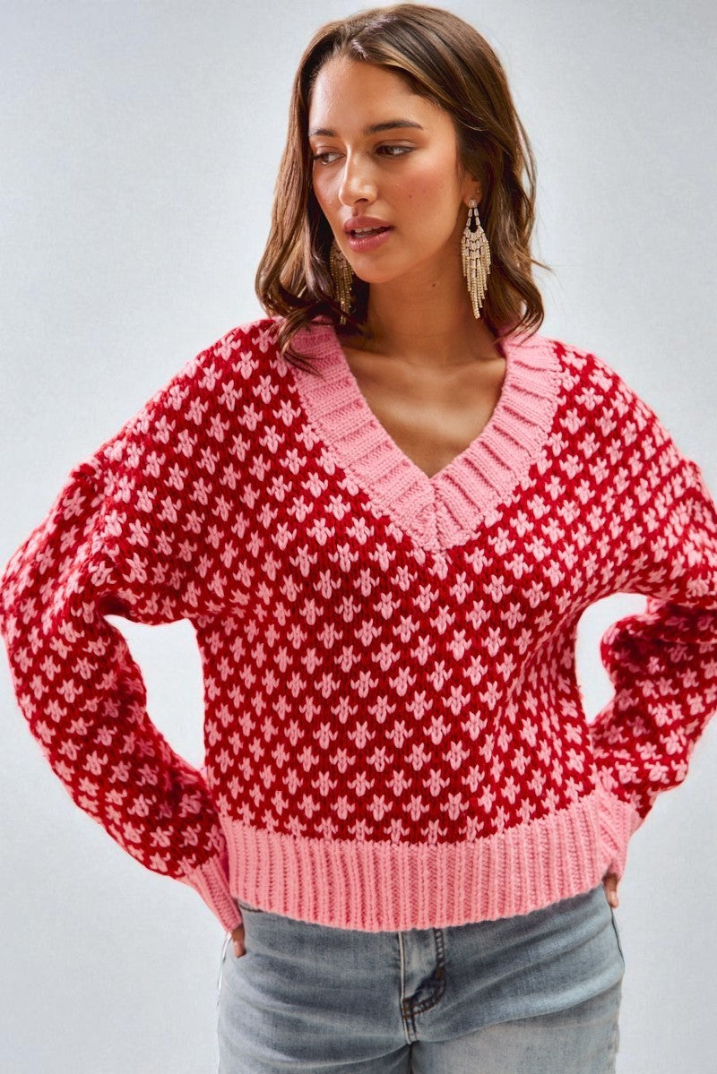 Woman wearing a red and pink patterned sweater against a gray background