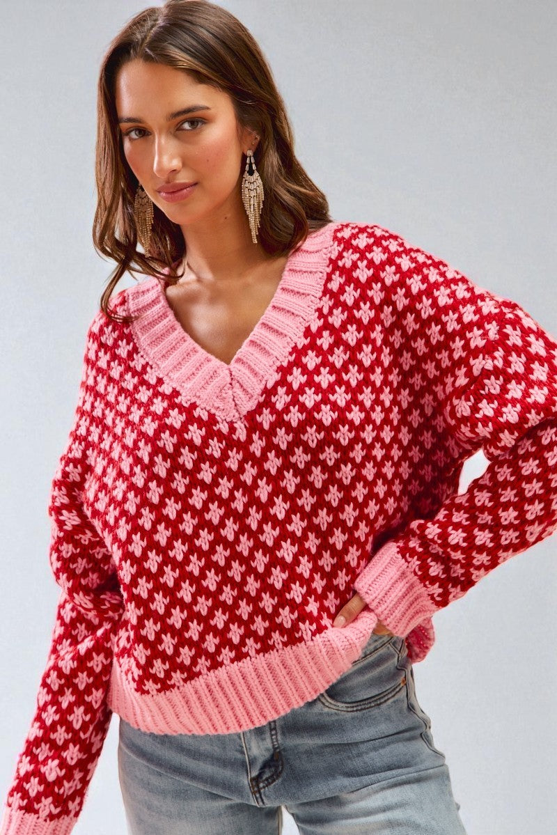 Woman wearing a red and pink patterned sweater against a gray background