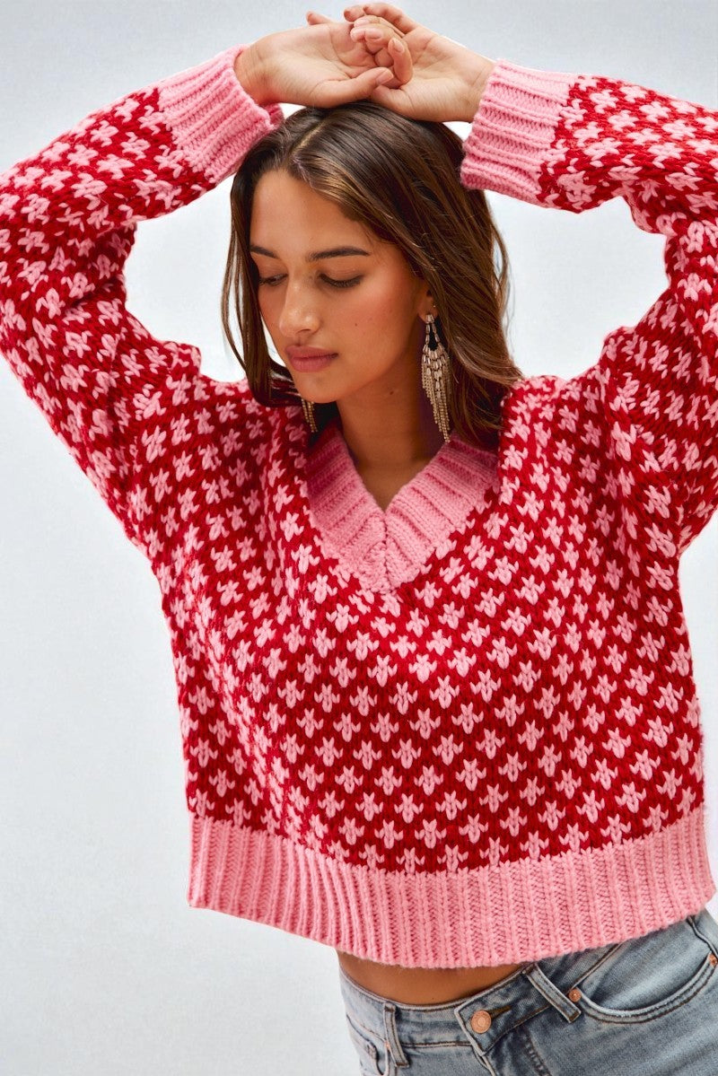 Woman wearing a red and pink patterned sweater against a plain background