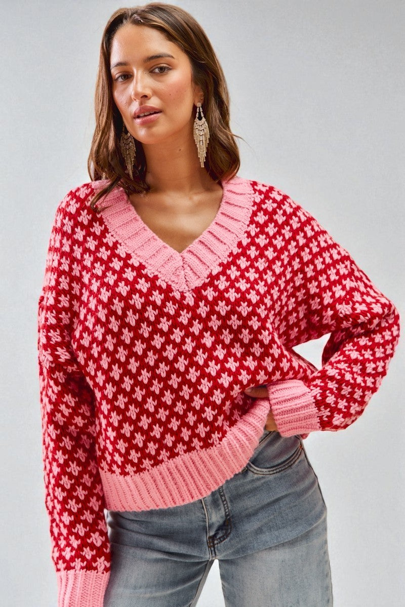 Woman wearing a red and pink patterned sweater against a gray background