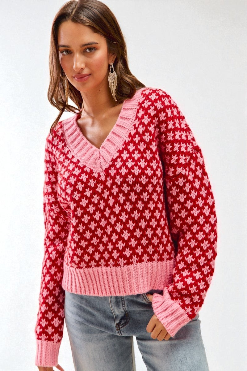 Woman wearing a red and pink patterned sweater against a white background