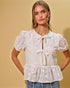 Woman wearing a white lace blouse with puff sleeves against a yellow background