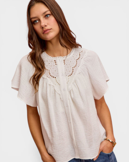 Woman wearing a white lace top on a plain background